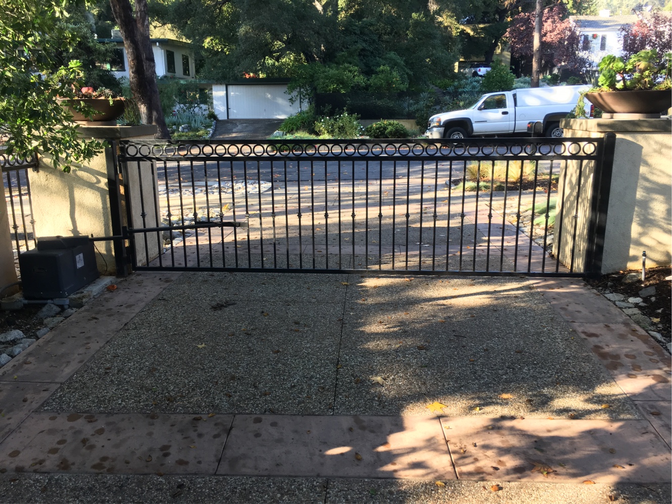 Black iron slide gate with spear-top pickets across a residential driveway in Sherman Oaks, CA