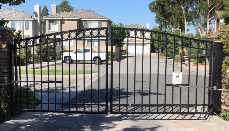 Arched black wrought iron double driveway gate at a residential community entrance in Granada Hills, CA