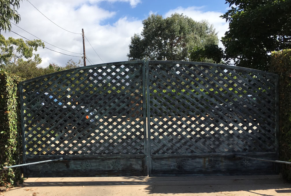 Arched green lattice-pattern double driveway gate framed by trees in Eagle Rock, CA
