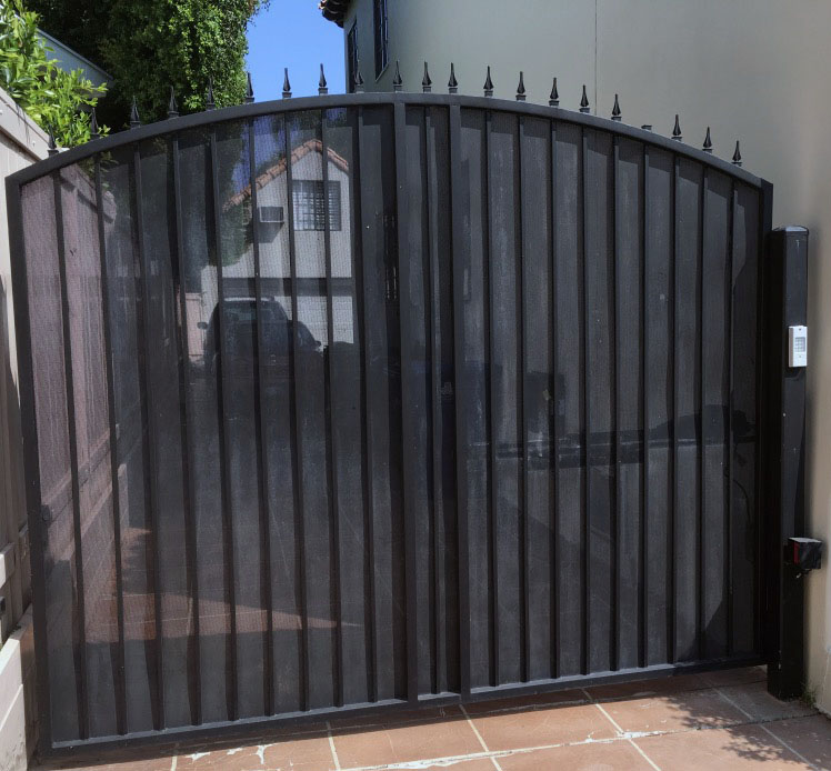 Arched black iron security gate with spear-top pickets beside a home in Van Nuys, CA