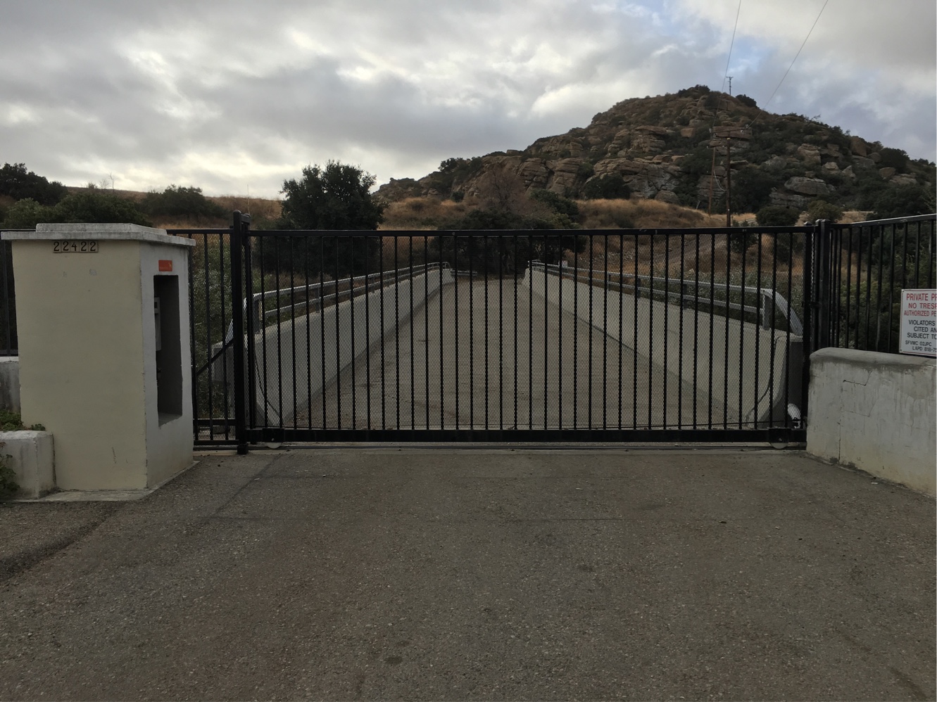 Black iron slide gate at a hillside estate entry below the Chatsworth rock formations, CA