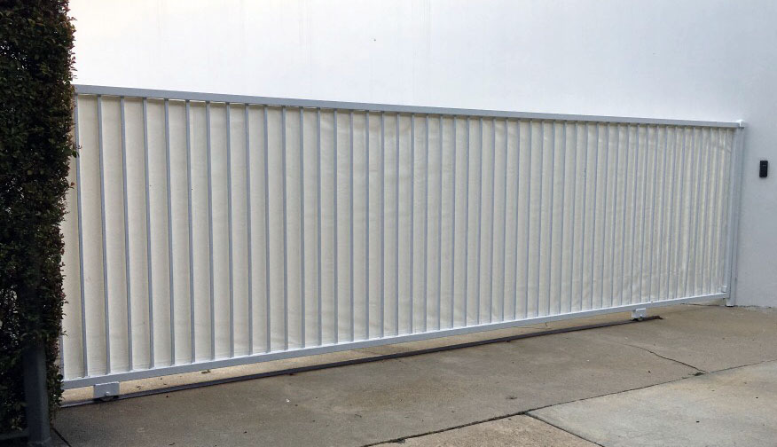 White vertical-panel steel slide gate across a commercial driveway in San Fernando, CA