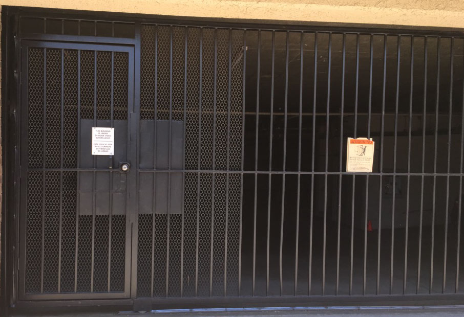 Black steel garage security gate with pedestrian door and mailbox at an apartment building in North Hollywood, CA