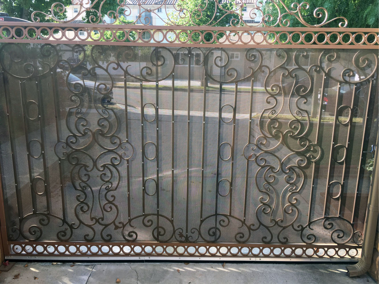 Black wrought iron slide gate with ornate scrollwork panels across a residential driveway in Tujunga, CA