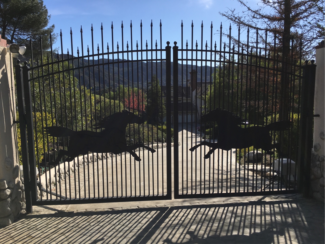 Black iron ranch gate with running horse silhouettes and spear-top pickets in Santa Rosa Valley, CA