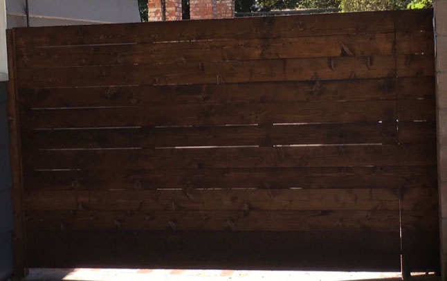 Horizontal wood-plank privacy slide gate across a residential driveway in Arleta, CA