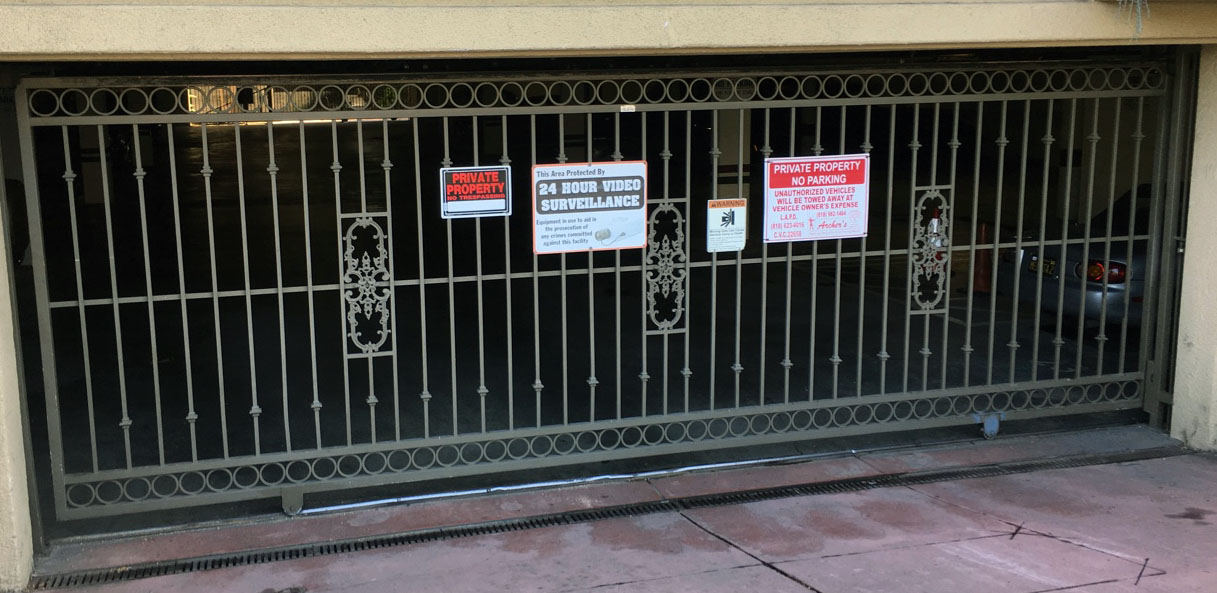 Black iron garage security gate with ornate scroll panels at an apartment parking entrance in North Hollywood, CA
