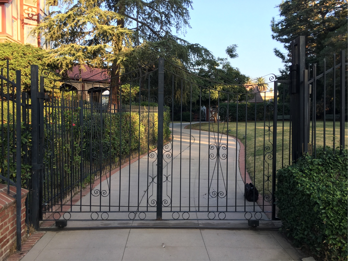 Black iron pedestrian gate and fence along a tree-lined walkway in Santa Rosa Valley, CA