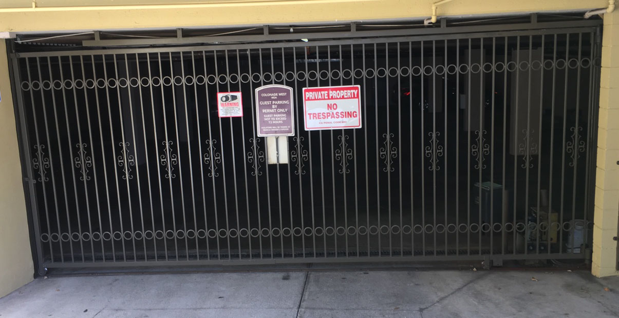Black iron garage security gate with scroll accents at an apartment building parking entrance in Pasadena, CA