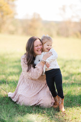 mother tickling toddler girl outside