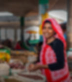 Femme souriante au marché local, entourée d'épices comoriennes, illustrant le savoir-faire traditionnel et la fabrication loc
