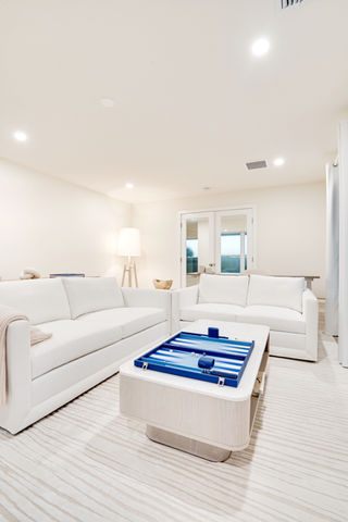 Modern living room with white sofas and blue accents.