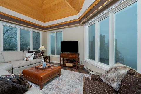 Cozy living room with large windows and wooden ceiling.