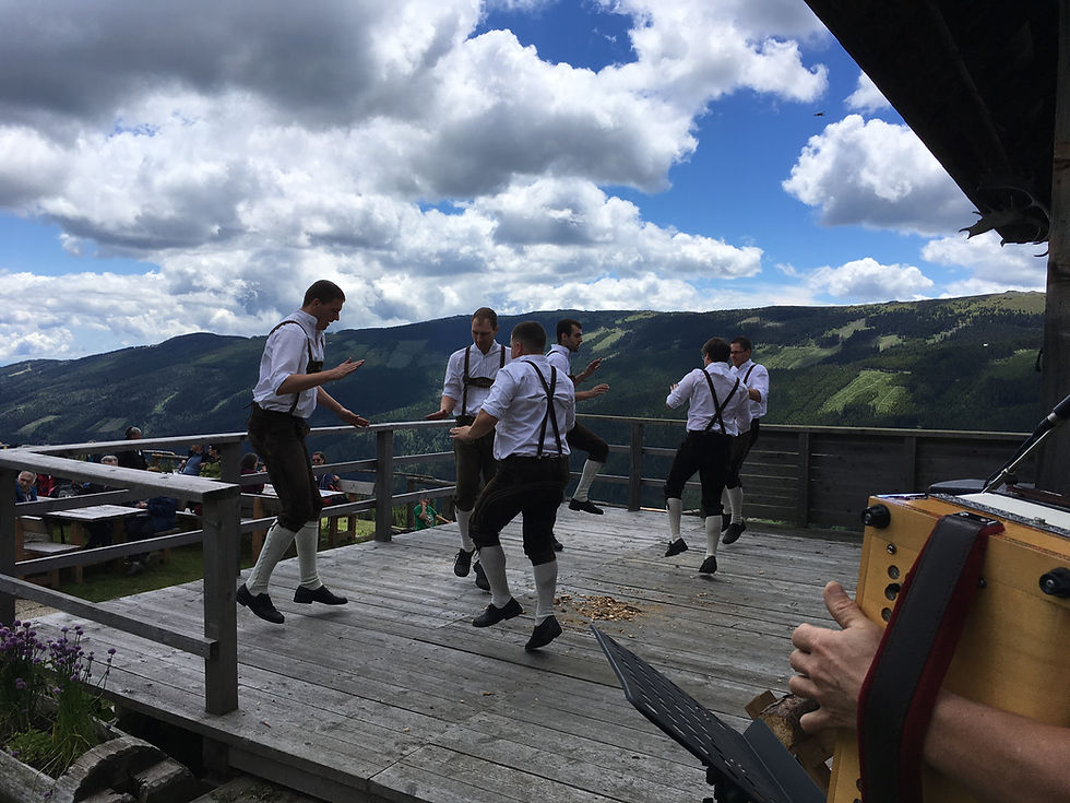 Traditioneller Schuhplattler Tanz von Männern auf einer idyllischen Alm.