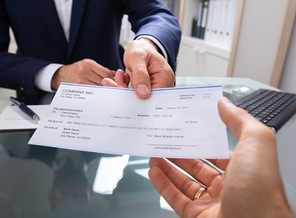 Man handing over a check to another person.