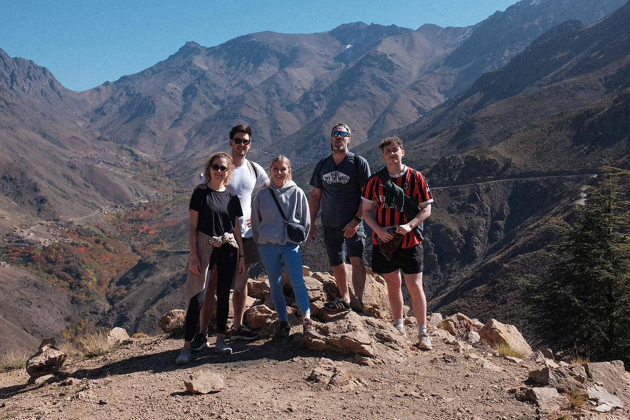 Radouane accompagné d’un groupe de randonneurs au col de Tizi n’Tamatert en direction du sommet, avec vue sur le village de Tachedirt dans le Haut Atlas, Maroc