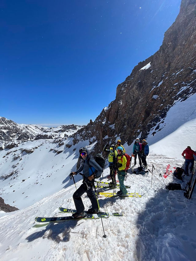 Ski touring group preparing to ski down from Akioud summit in the High Atlas Mountains, Morocco, after crossing Tizi N’Akioud on the way towards Toubkal refuge.