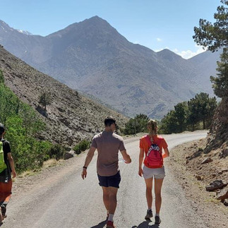 Hikers walking along a mountain road near Imlil village after completing a day hike in the Atlas Mountains, with guide Radouane on the left