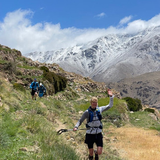 Trail runners near Azib Likemt with snow-covered Atlas peaks in the background, Morocco