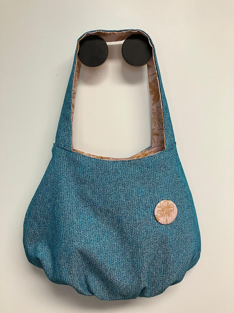 Sac à main bleu avec bouton rose, accroché au mur, Les Baladeuses.
