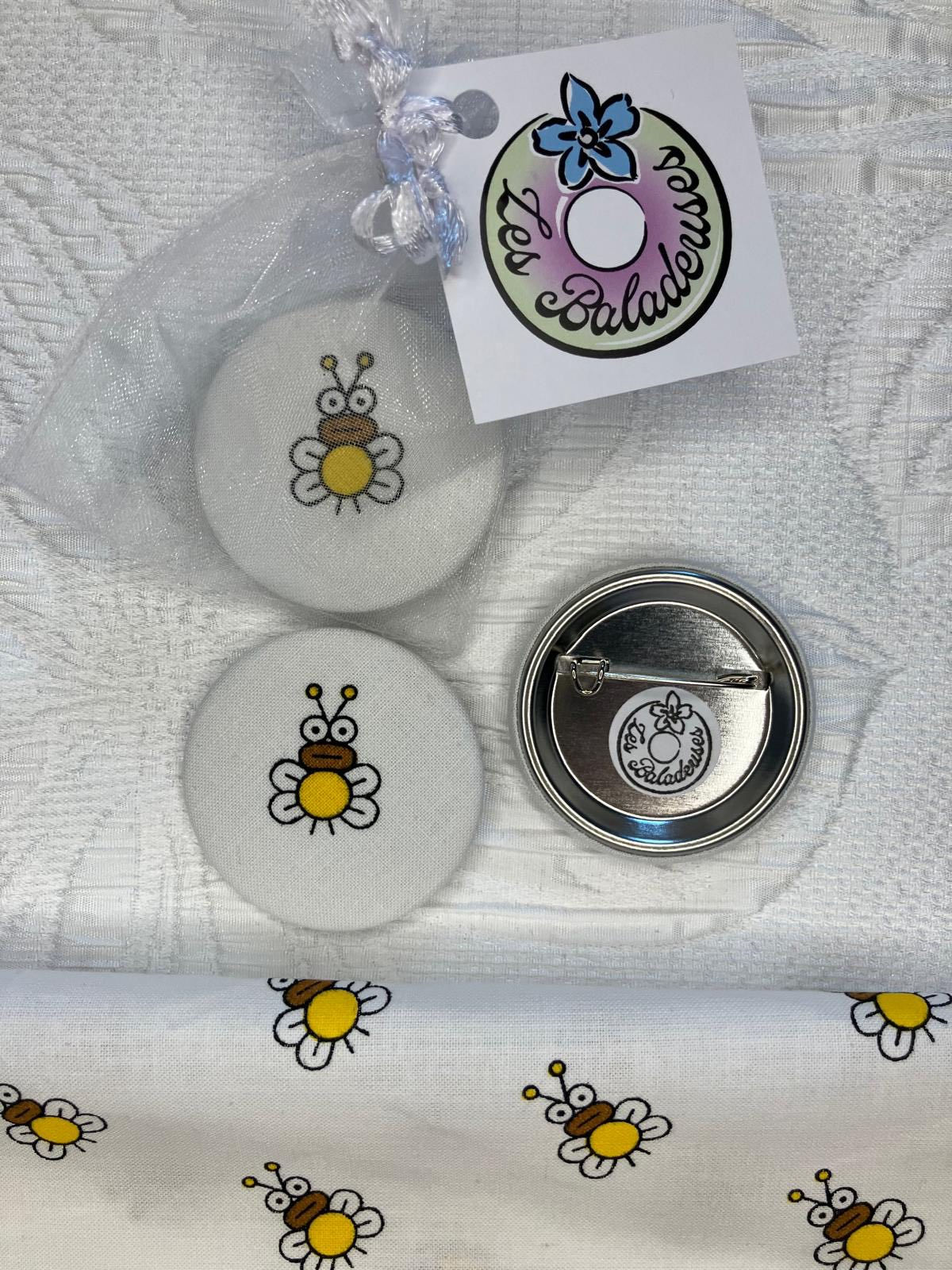 Deux broches abeilles et Les Baladeuses, broches artisanales, avec un imprimé floral.