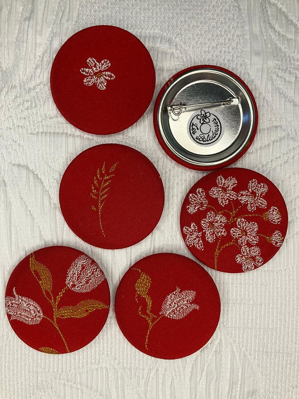 Lot de 3 Broches - Linge 3, plusieurs broches rondes rouges avec différents motifs floraux.