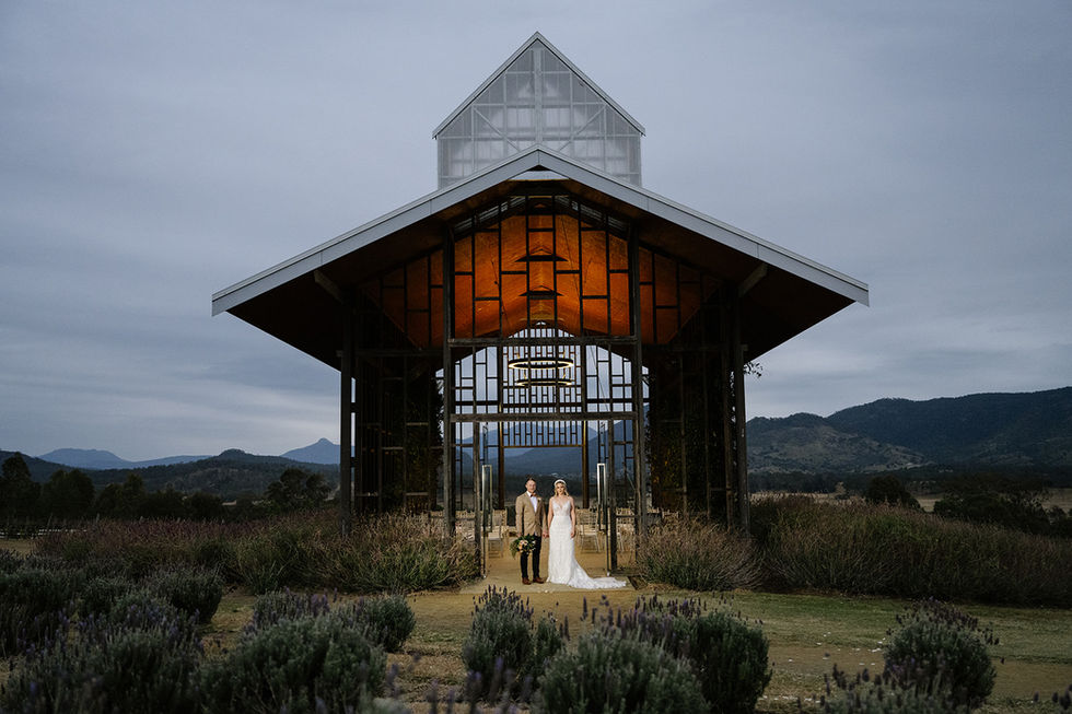 Bride and groom standing beneath the illuminated chapel at dusk in the Scenic Rim.