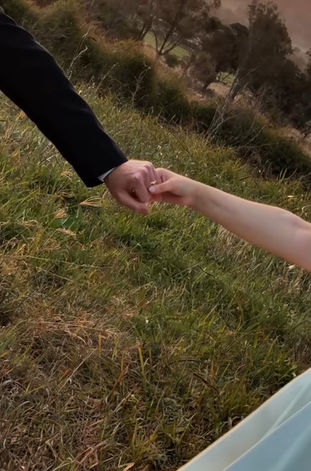 Bride and groom holding hands while walking through the Scenic Rim countryside at sunset.