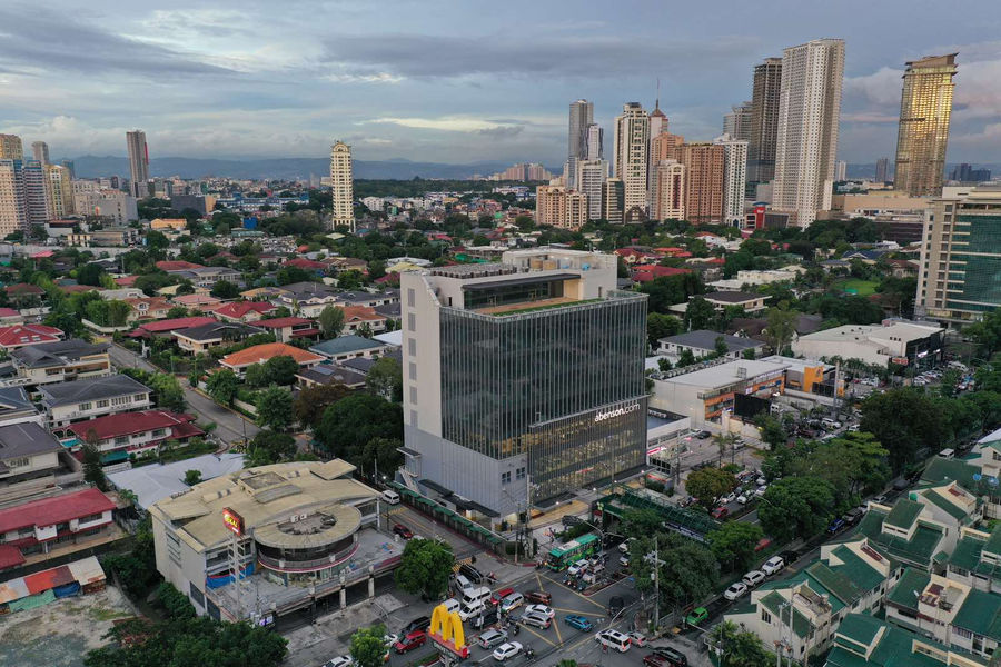Abenson Design Center in San Juan City stands out as a modern architectural landmark. This aerial view showcases the building's prominent presence in the urban landscape, with a backdrop of the Manila skyline. The design reflects a contemporary interpretation of Philippine architectural principles, creating a visually striking and functional commercial space.