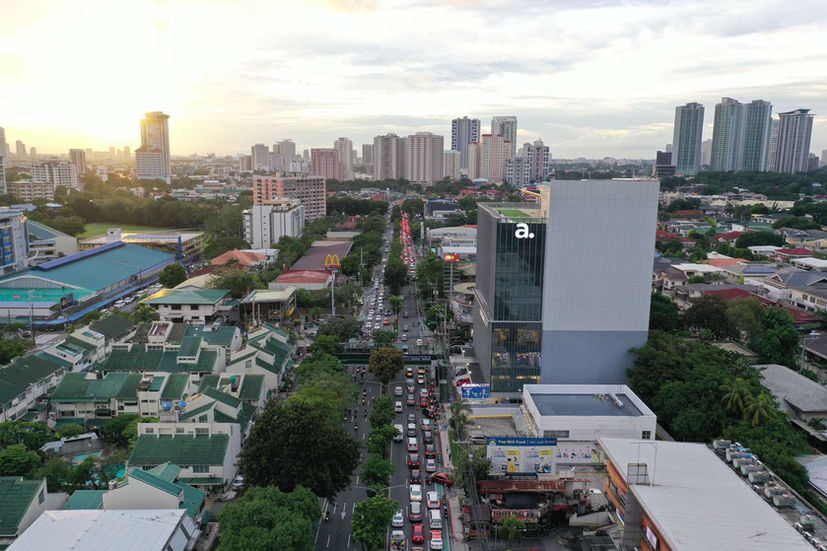 Abenson Design Center in San Juan City stands out as a modern architectural landmark. This aerial view showcases the building's prominent presence in the urban landscape, with a backdrop of the Manila skyline. The design reflects a contemporary interpretation of Philippine architectural principles, creating a visually striking and functional commercial space.