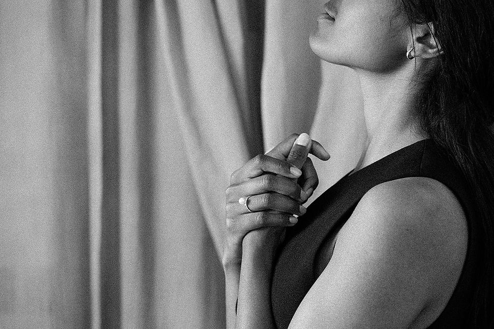 Thumbnail: black and white image of a model holding her head up in a side profile with hands crossed over chest displaying a gold ring a