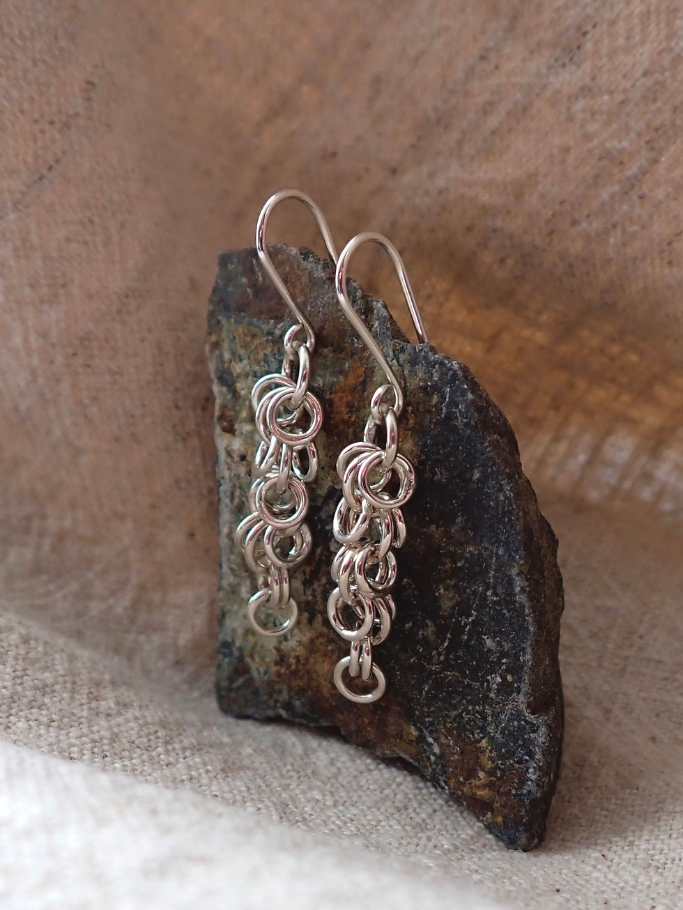 Ruth Gilmour silver drop earrings with circular links resting on natural stone. Bright finish stands out against earthy tones