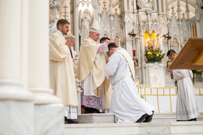 Archbishop Samuel Aquila performs the Laying of the Hands for Deacon Kevin Kasel during his ordination to the priesthood. (Photo by Daniel Petty/Denver Catholic)