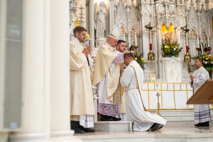 Archbishop Samuel Aquila performs the Laying of the Hands for Deacon Anthony Phan during his ordination to the priesthood. (Photo by Daniel Petty/Denver Catholic)