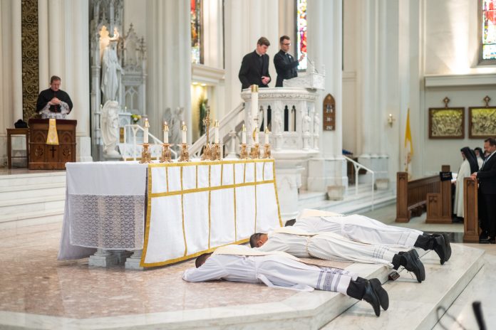 Deacons lay prostrate during the litany of saints during their priestly ordination. (Photo by Daniel Petty/Denver Catholic)