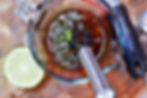 Glass measuring cup with dark sauce and lime zest. A whisk is inside the cup. Half lime is on a wooden surface. Text reads "Pyrex," "Microplane."