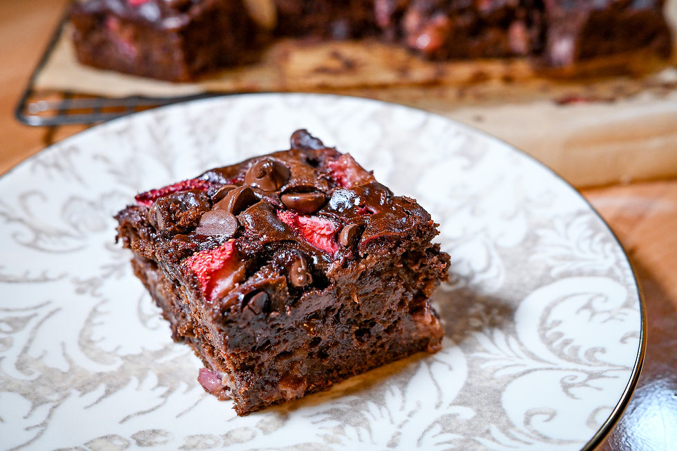 Chocolate brownie with strawberries and chocolate chips on a decorative plate. Soft lighting creates a warm, inviting mood.