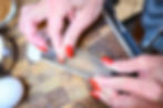 Hands with red nails grating food on a microplane over a wooden cutting board, with an egg nearby.