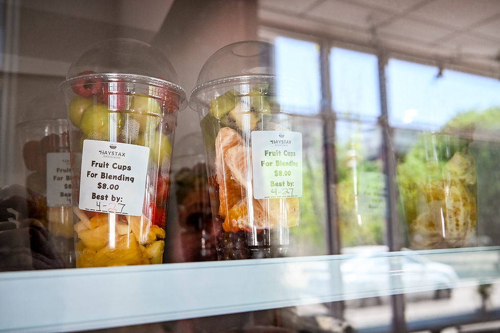 Fruit cups with mixed fruits are displayed in a glass case. Labels show "Fruit Cups For Blending $8.00," with a best-by date of 4-27.