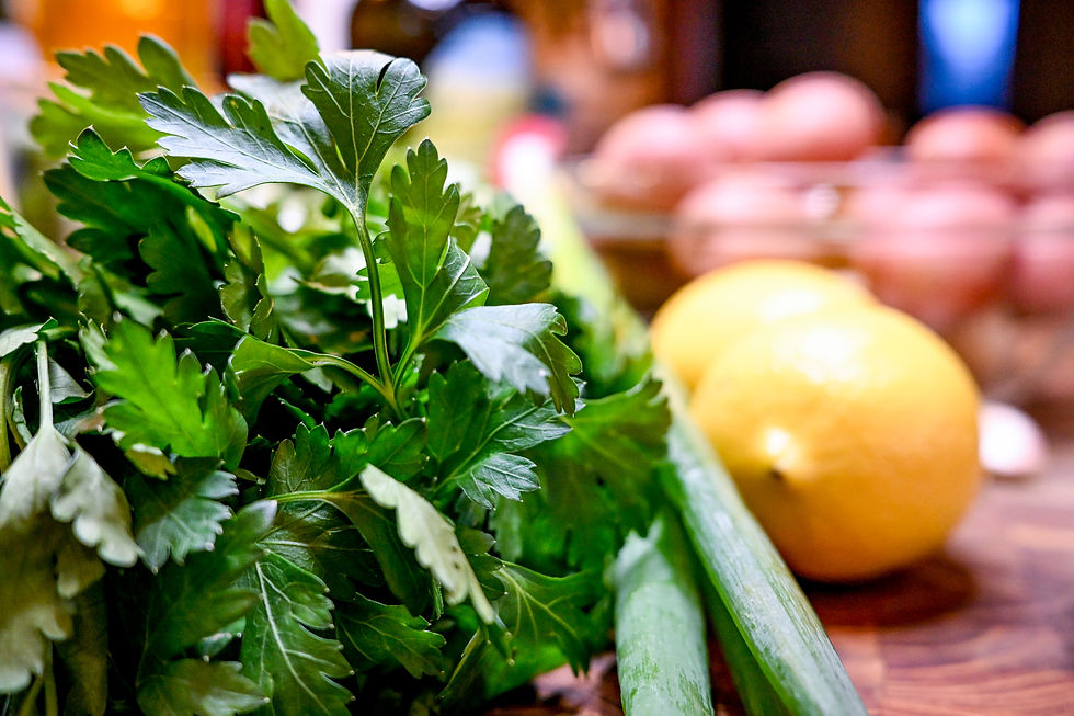 Fresh parsley and lemons on a wooden kitchen counter with blurred background. Lush green leaves and vibrant yellow fruits create a lively scene.