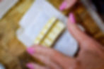 Hands with pink nails slicing butter on parchment paper atop a wooden cutting board, reflecting a kitchen setting.