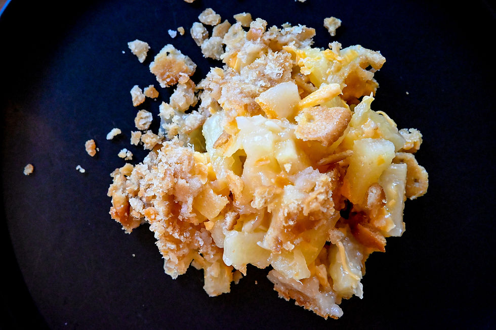 A serving of cheesy baked macaroni with a golden breadcrumb crust on a dark plate, showcasing a crunchy, inviting texture.