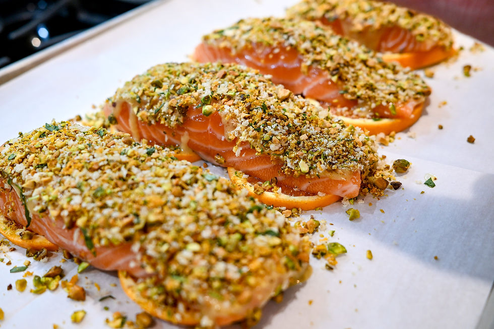 Salmon fillets with a crunchy pistachio crust on parchment paper, arranged neatly. The vibrant orange and green colors stand out.