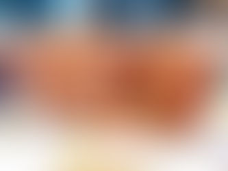 Close-up of a sliced carrot muffin with visible raisins on a wooden surface. Other whole muffins in the blurred background. Warm tones.