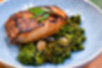 Grilled salmon fillet with sesame seeds and green garnish on a bed of broccolini, served on a blue plate, creating a fresh, appetizing look.
