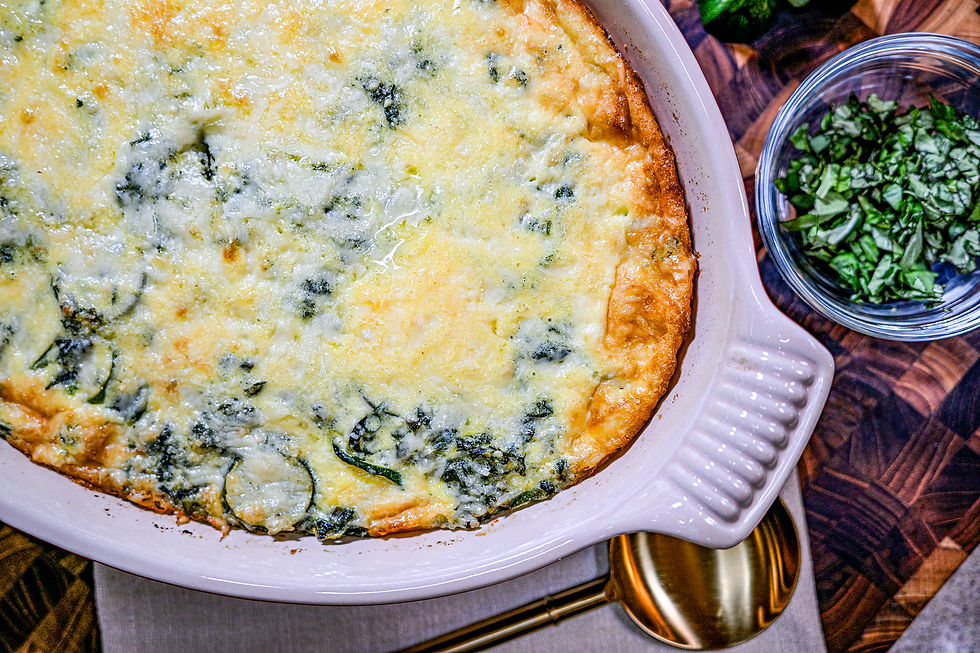 Golden spinach frittata in a white dish on a wooden table, next to a bowl of chopped greens and a brass spoon, creating a warm, cozy vibe.