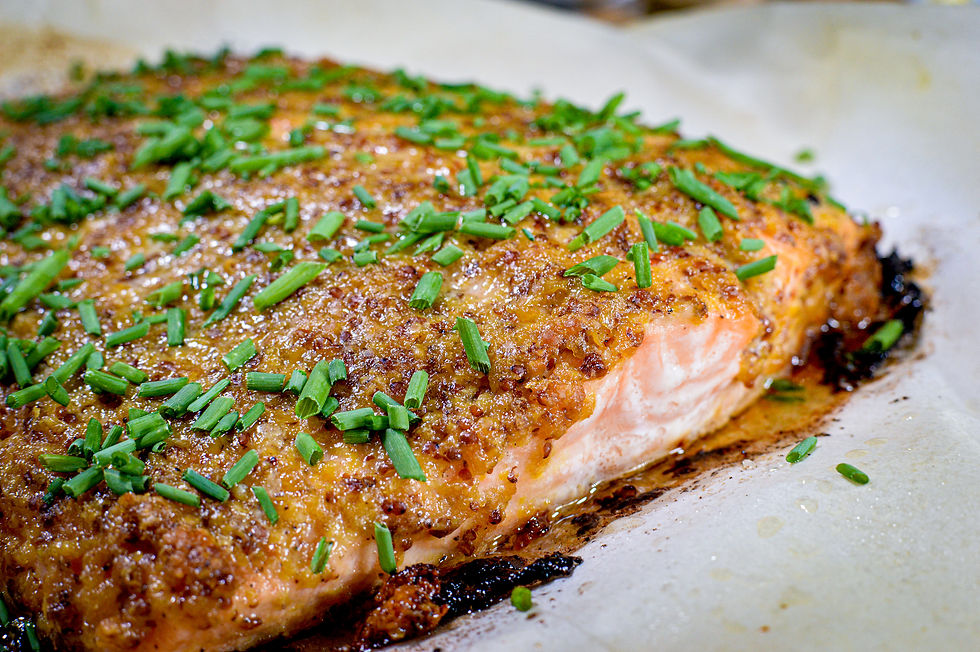 Close-up of a cooked salmon fillet topped with chopped chives on a baking sheet. The crust is golden and crispy, adding a savory appeal.