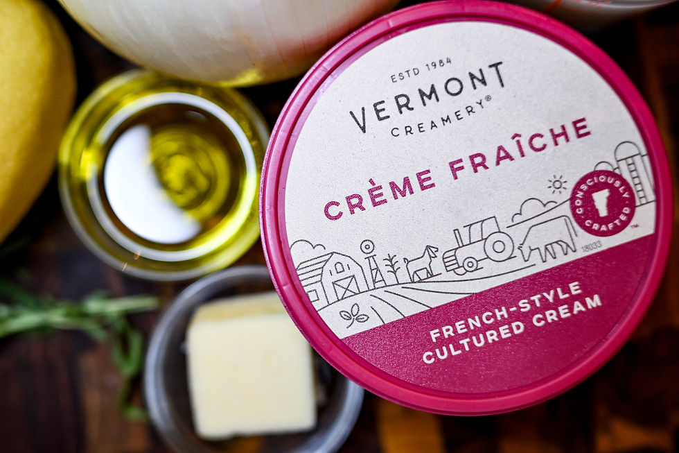 Vermont Creamery Crème Fraîche container with farm illustration, surrounded by ingredients like olive oil, butter, and onions.