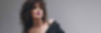 Woman with curly hair and pink lipstick in a black off-shoulder top against a gray background, exuding confidence and style. 2025 GLOBAL TRENDS: Beauty and Personal Care DiMotta Strategic Adriana Motta.