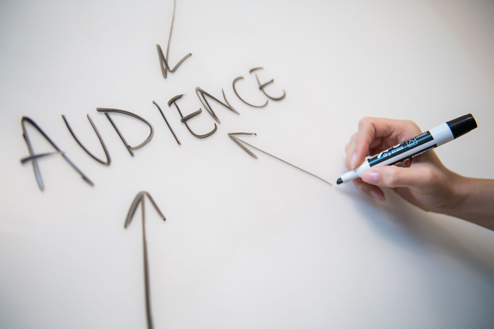 Woman drawing arrow on blackboard pointing to the word "audience", symbolizing targeting the audience.